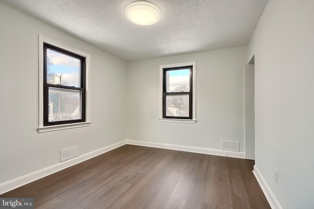 empty room featuring a textured ceiling and dark hardwood / wood-style flooring