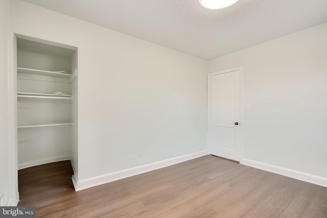 unfurnished bedroom with hardwood / wood-style flooring, a textured ceiling, and a closet