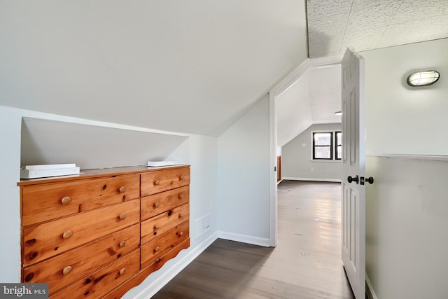 additional living space featuring vaulted ceiling and dark wood-type flooring