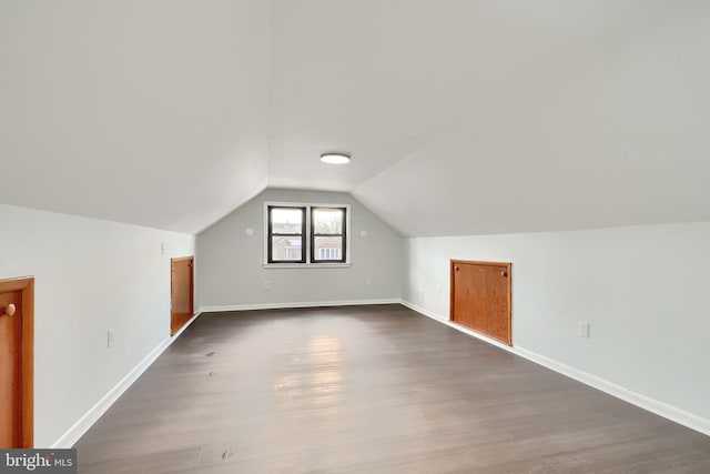 bonus room with dark wood-type flooring and lofted ceiling