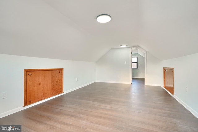 additional living space featuring light hardwood / wood-style floors and vaulted ceiling