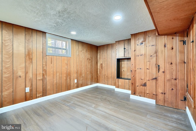 basement featuring light wood-type flooring and wooden walls