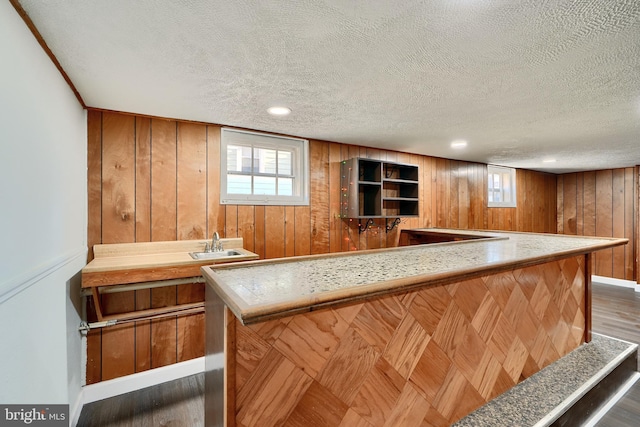 bar with a textured ceiling, wooden walls, and a healthy amount of sunlight