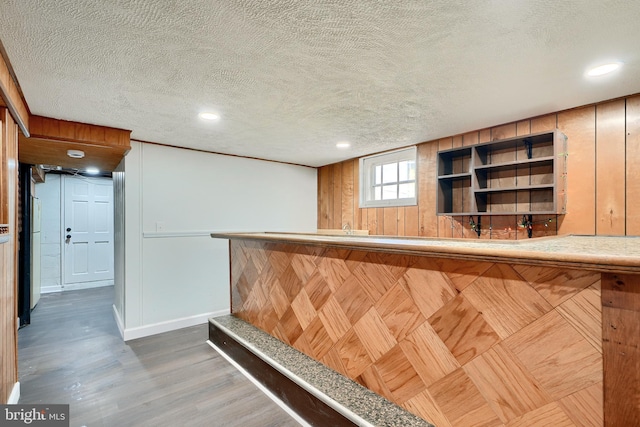 bar featuring a textured ceiling, dark hardwood / wood-style flooring, and wooden walls