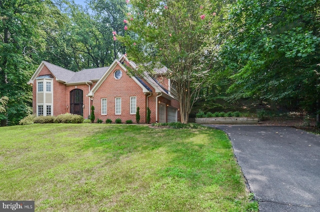 traditional-style home with driveway, brick siding, and a front lawn