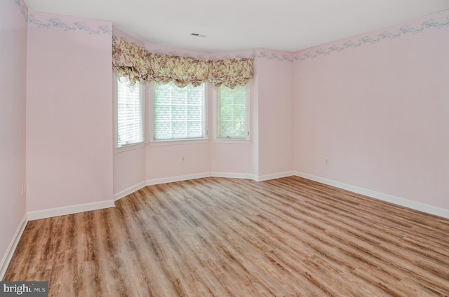 empty room featuring baseboards, visible vents, and light wood-style flooring