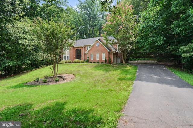 view of front facade with a front yard, aphalt driveway, and brick siding