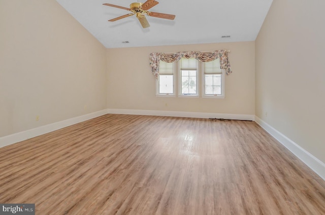 empty room featuring vaulted ceiling, visible vents, a ceiling fan, baseboards, and light wood-type flooring