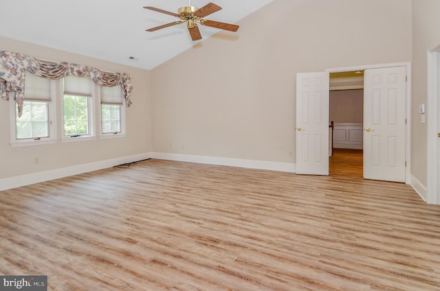 empty room with ceiling fan, light wood-type flooring, and vaulted ceiling