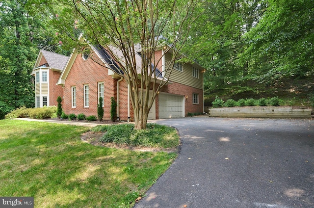 traditional-style home with a garage, a front lawn, aphalt driveway, and brick siding