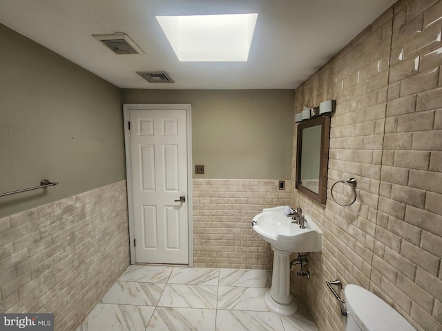 bathroom with toilet and tile walls