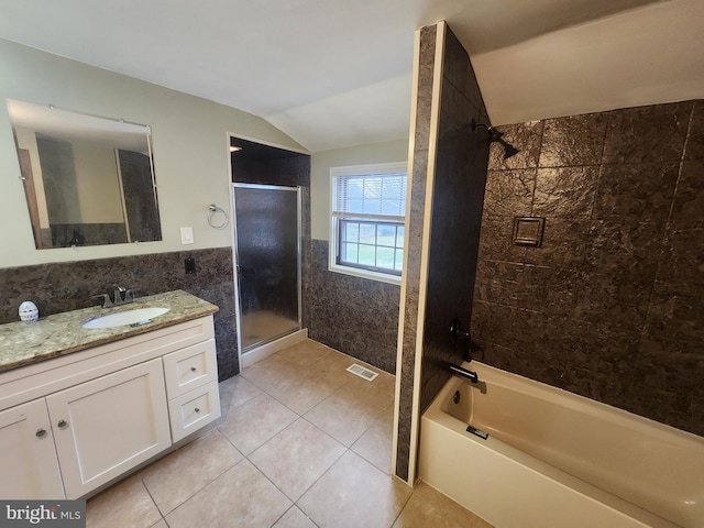 bathroom with vanity, tiled shower / bath, vaulted ceiling, tile patterned flooring, and tile walls