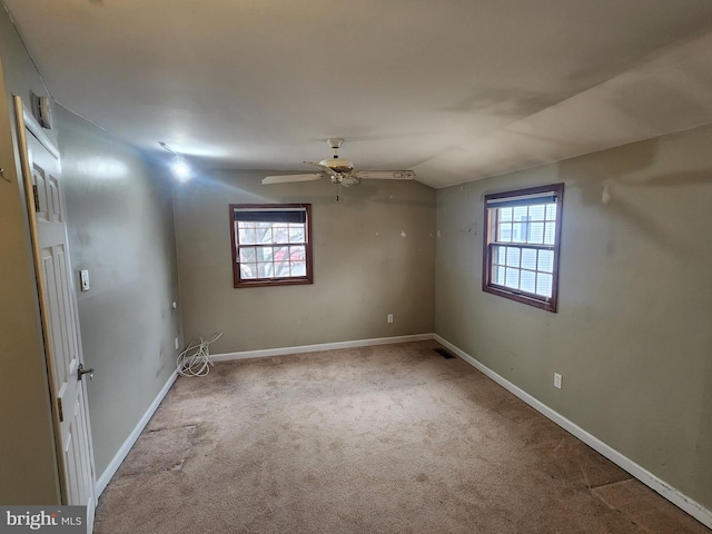 carpeted spare room featuring vaulted ceiling, a wealth of natural light, and ceiling fan