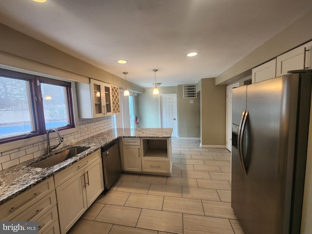 kitchen with kitchen peninsula, appliances with stainless steel finishes, light stone counters, and sink