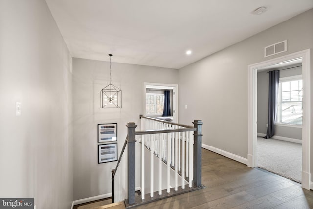 stairs with hardwood / wood-style floors and an inviting chandelier