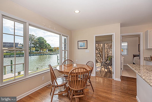 dining area featuring a water view and dark hardwood / wood-style floors