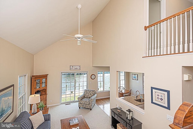 carpeted living room featuring sink, ceiling fan, and a high ceiling