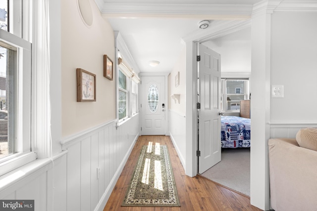 hall with a wainscoted wall, crown molding, and hardwood / wood-style flooring