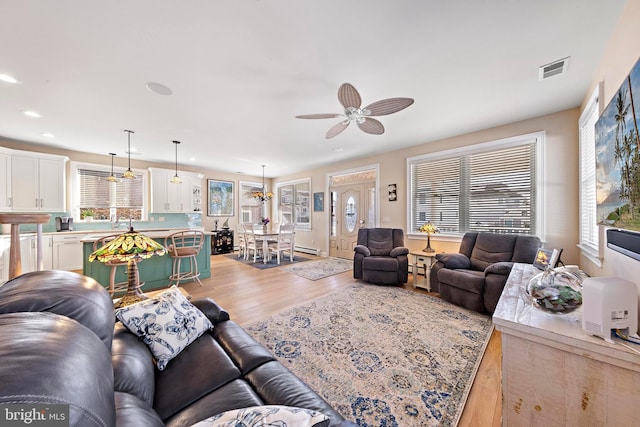 living room with a wealth of natural light, light wood-type flooring, and ceiling fan