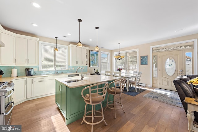 kitchen featuring high end range, hanging light fixtures, a kitchen island with sink, and sink