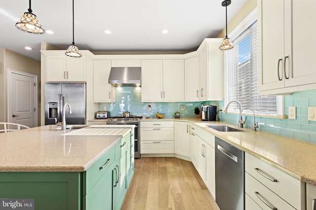 kitchen featuring sink, wall chimney exhaust hood, pendant lighting, white cabinets, and appliances with stainless steel finishes