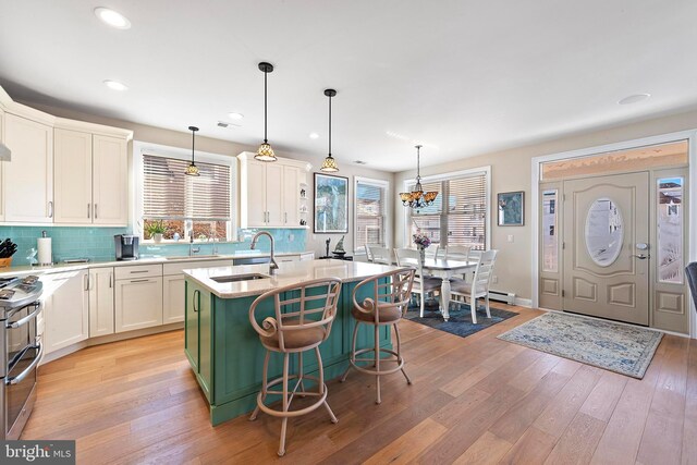 kitchen featuring pendant lighting, sink, stainless steel range oven, and an island with sink