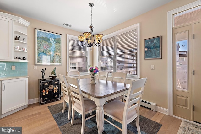 dining area with light wood-type flooring and an inviting chandelier