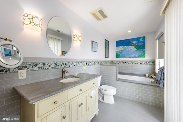 bathroom featuring a bathing tub, tile patterned flooring, toilet, vanity, and tile walls