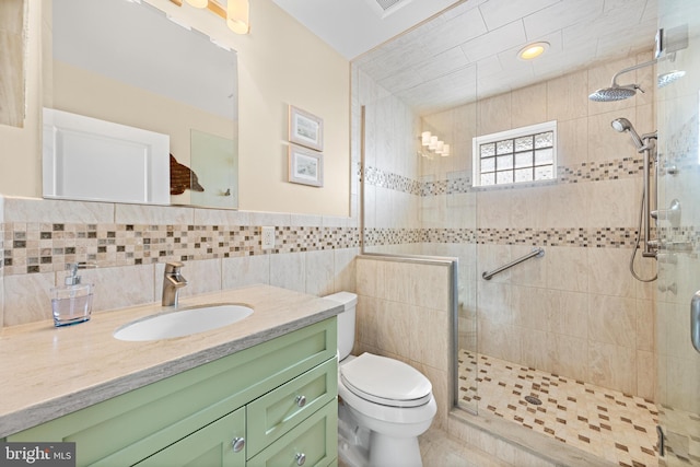 bathroom featuring vanity, a shower with door, toilet, and tile walls