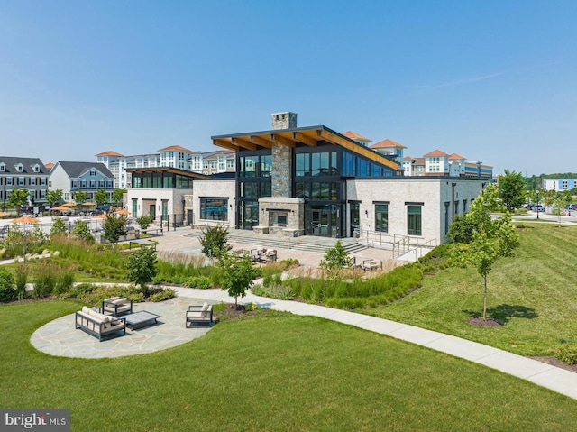 rear view of property with an outdoor stone fireplace, a yard, and a patio