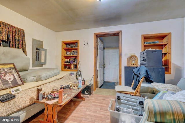 living room featuring built in shelves, electric panel, and light hardwood / wood-style floors