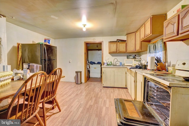 kitchen with light hardwood / wood-style floors, white appliances, sink, and light brown cabinetry