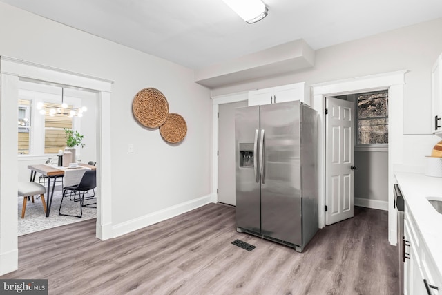 kitchen featuring white cabinetry, hardwood / wood-style floors, an inviting chandelier, and appliances with stainless steel finishes