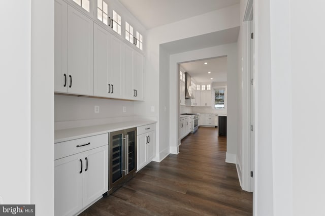 bar with stainless steel gas range oven, wall chimney exhaust hood, white cabinetry, dark hardwood / wood-style floors, and wine cooler