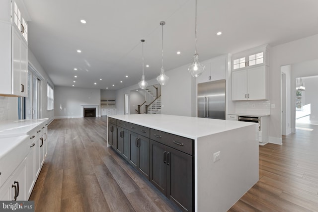 kitchen with backsplash, stainless steel built in fridge, decorative light fixtures, a large island, and white cabinetry