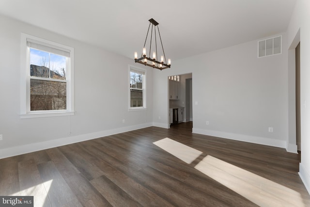 unfurnished dining area featuring dark hardwood / wood-style flooring and a chandelier