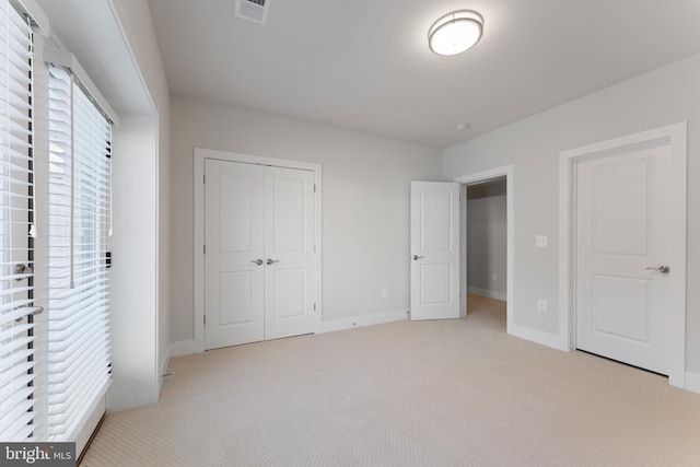 unfurnished bedroom with light carpet and a closet