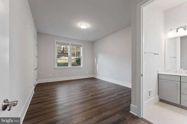 interior space with ensuite bathroom, sink, and dark wood-type flooring