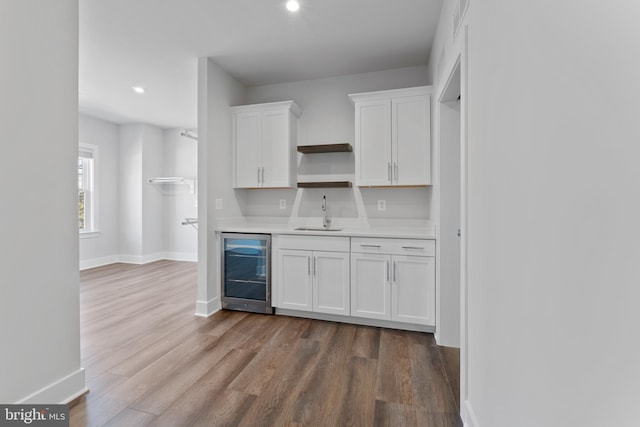 kitchen with white cabinets, hardwood / wood-style flooring, beverage cooler, and sink