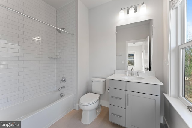 full bathroom with tiled shower / bath combo, a wealth of natural light, toilet, and vanity