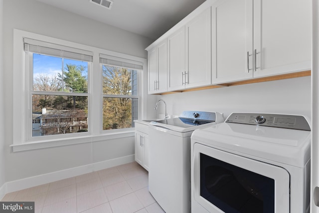 laundry area featuring cabinets, light tile patterned floors, sink, and washing machine and clothes dryer