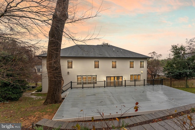 back house at dusk with a wooden deck