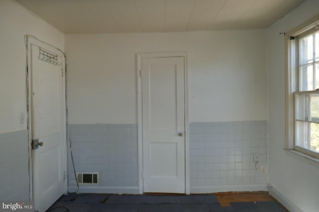 unfurnished room with tile walls