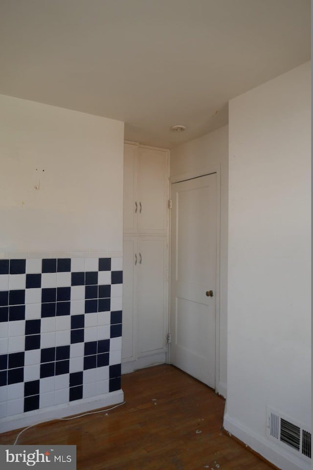 spare room with tile walls and dark wood-type flooring