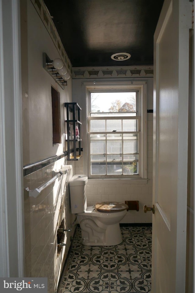 bathroom featuring tile patterned flooring, tile walls, and toilet