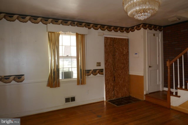 interior space with hardwood / wood-style floors, a chandelier, and brick wall