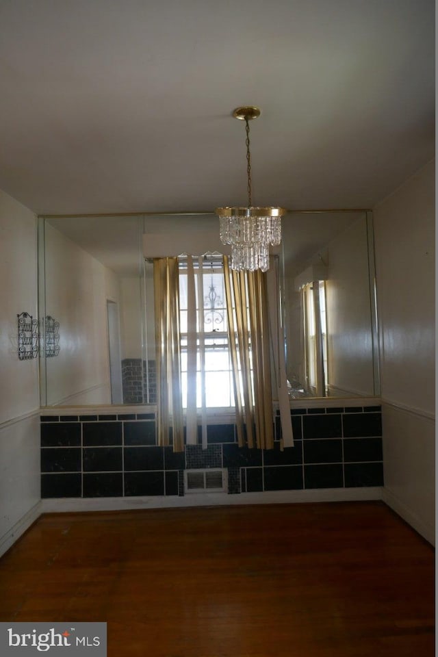 unfurnished dining area with dark hardwood / wood-style floors and a chandelier