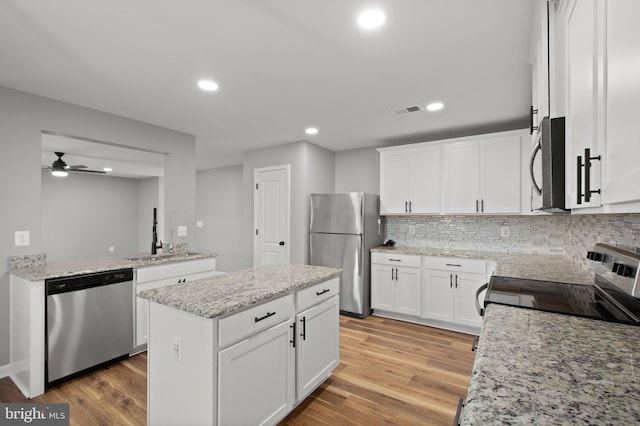 kitchen with ceiling fan, white cabinetry, stainless steel appliances, and light hardwood / wood-style flooring