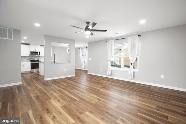 unfurnished living room featuring dark hardwood / wood-style flooring and ceiling fan