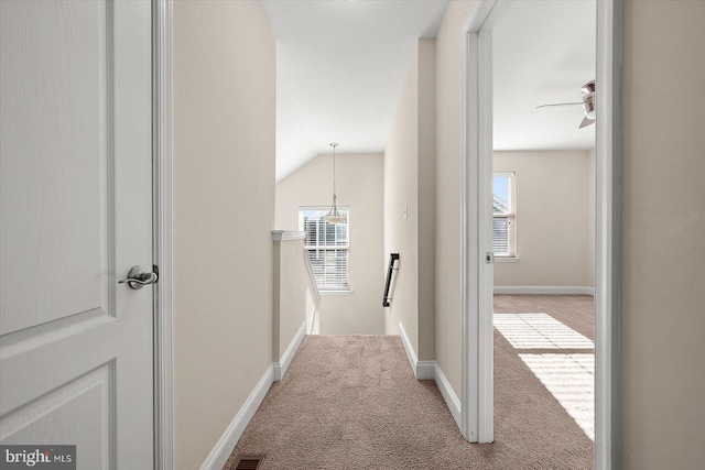 hallway with light colored carpet and lofted ceiling